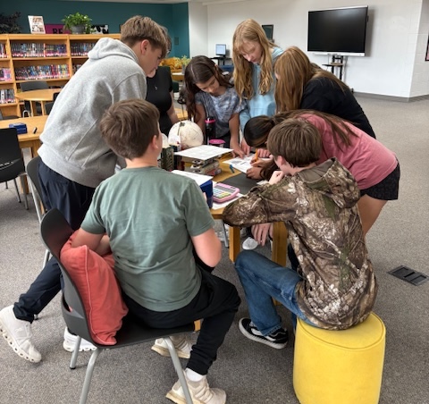 Kids huddled around a table paying the Pippa Park Escape Room